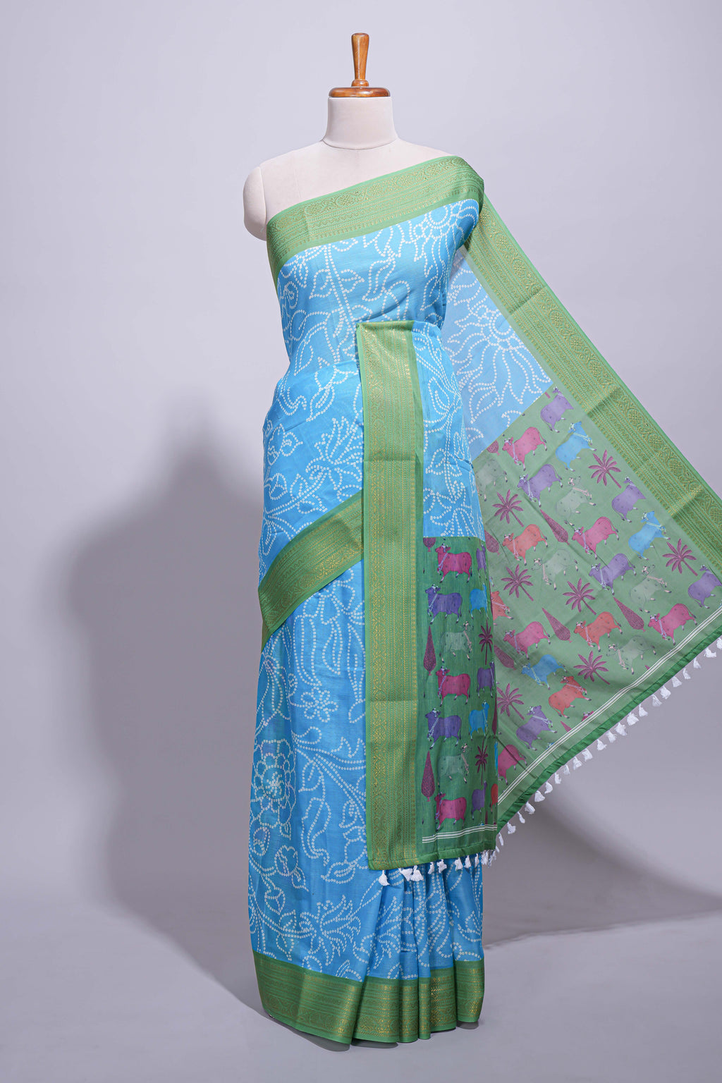 Blue linen saree with white dotted floral patterns with golden zari border and a multicolour pichwai motifs along with printed blouse