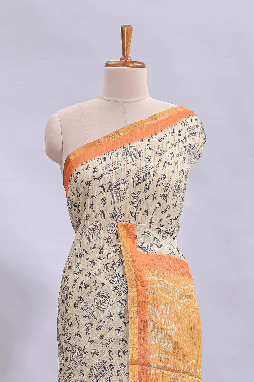 Beige tribal design warli print linen cotton saree with contrast orange zari border and floral design pallu