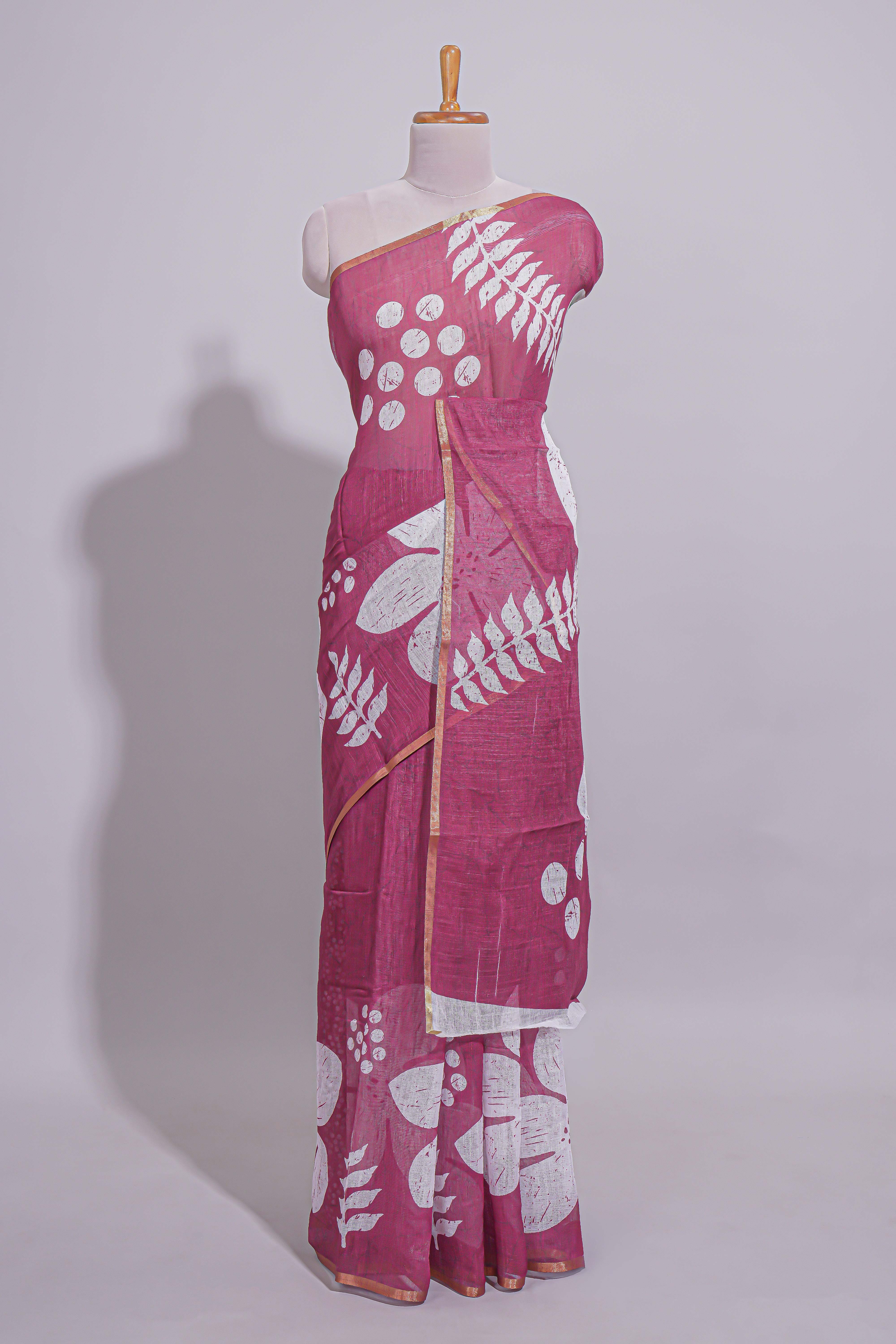 Rani pink linen saree with bold white floral and geometric prints finished with a subtle metallic border along with matching blouse