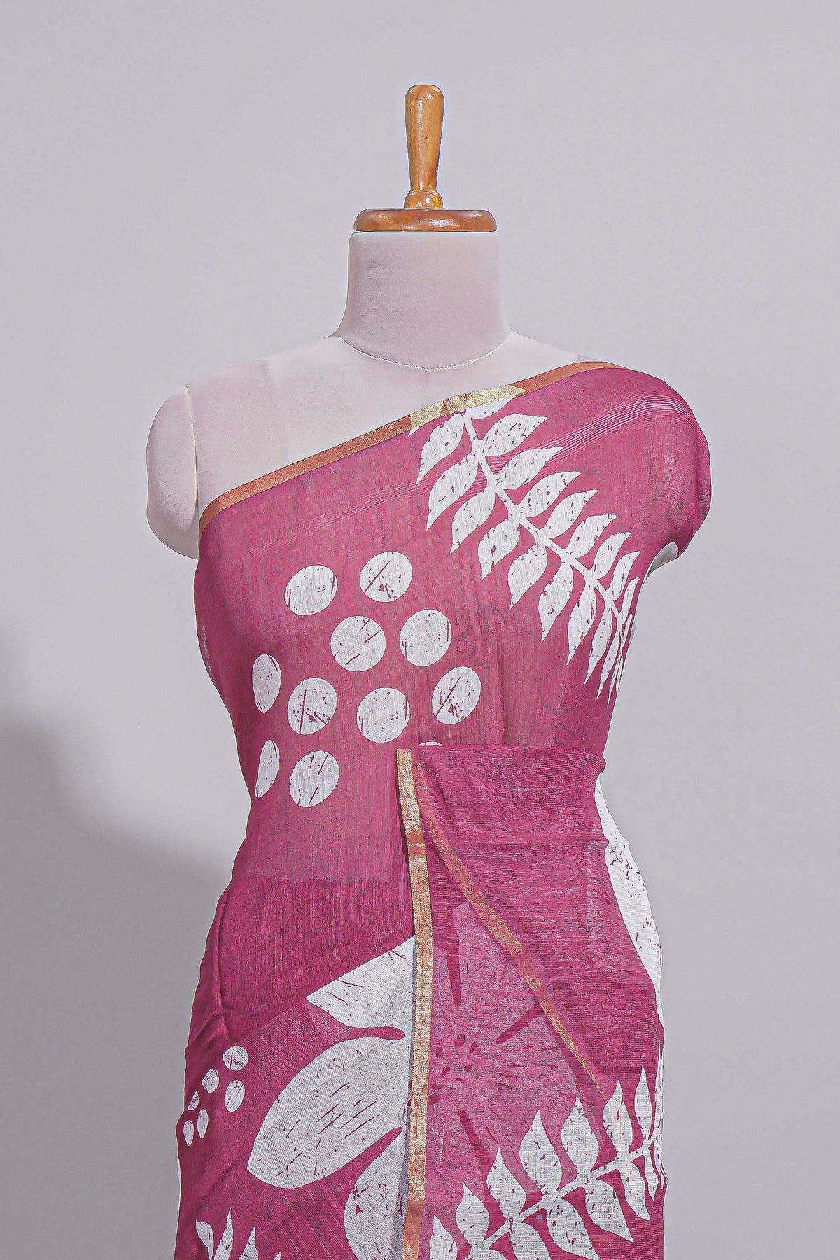 Rani pink linen saree with bold white floral and geometric prints finished with a subtle metallic border along with matching blouse