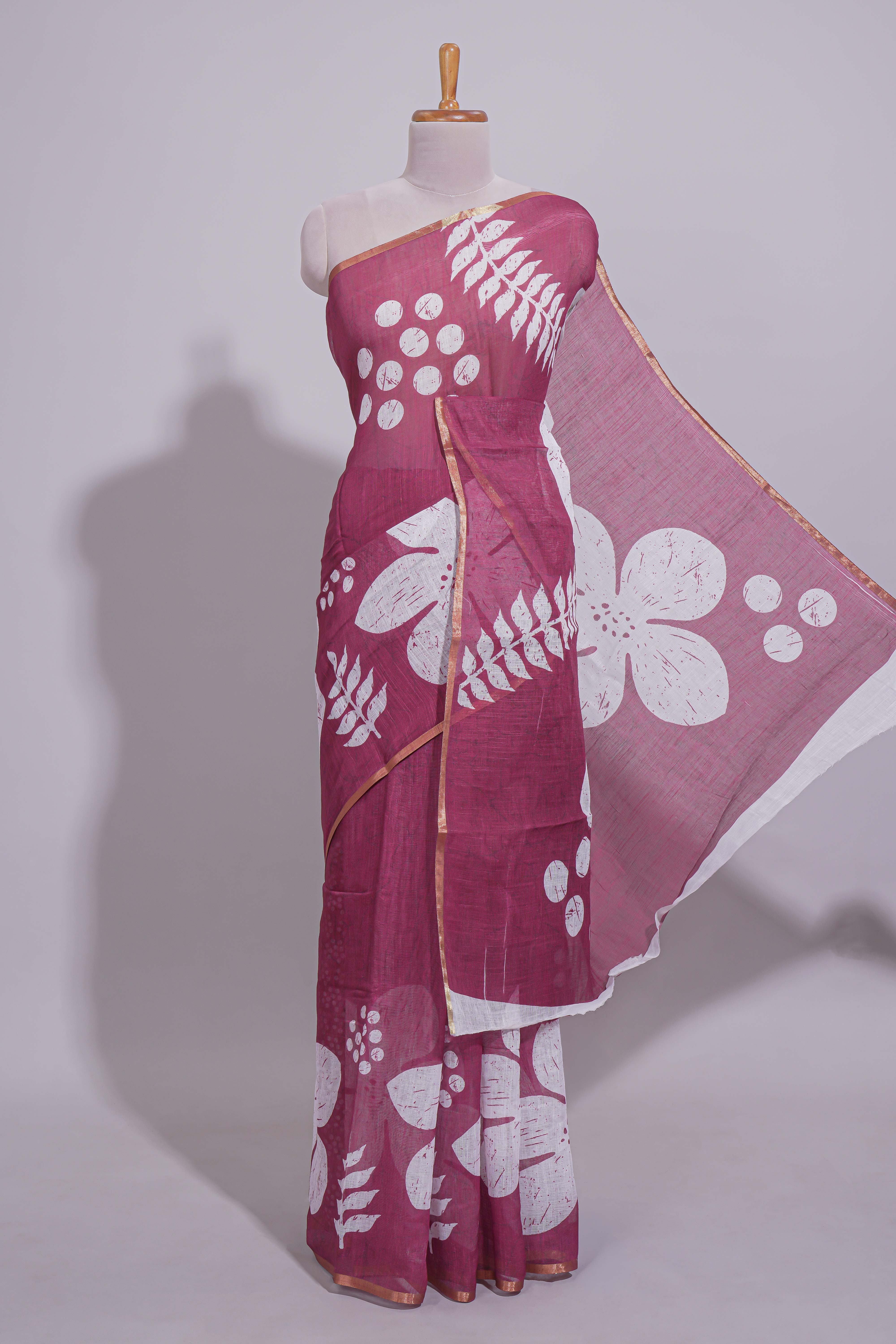 Rani pink linen saree with bold white floral and geometric prints finished with a subtle metallic border along with matching blouse
