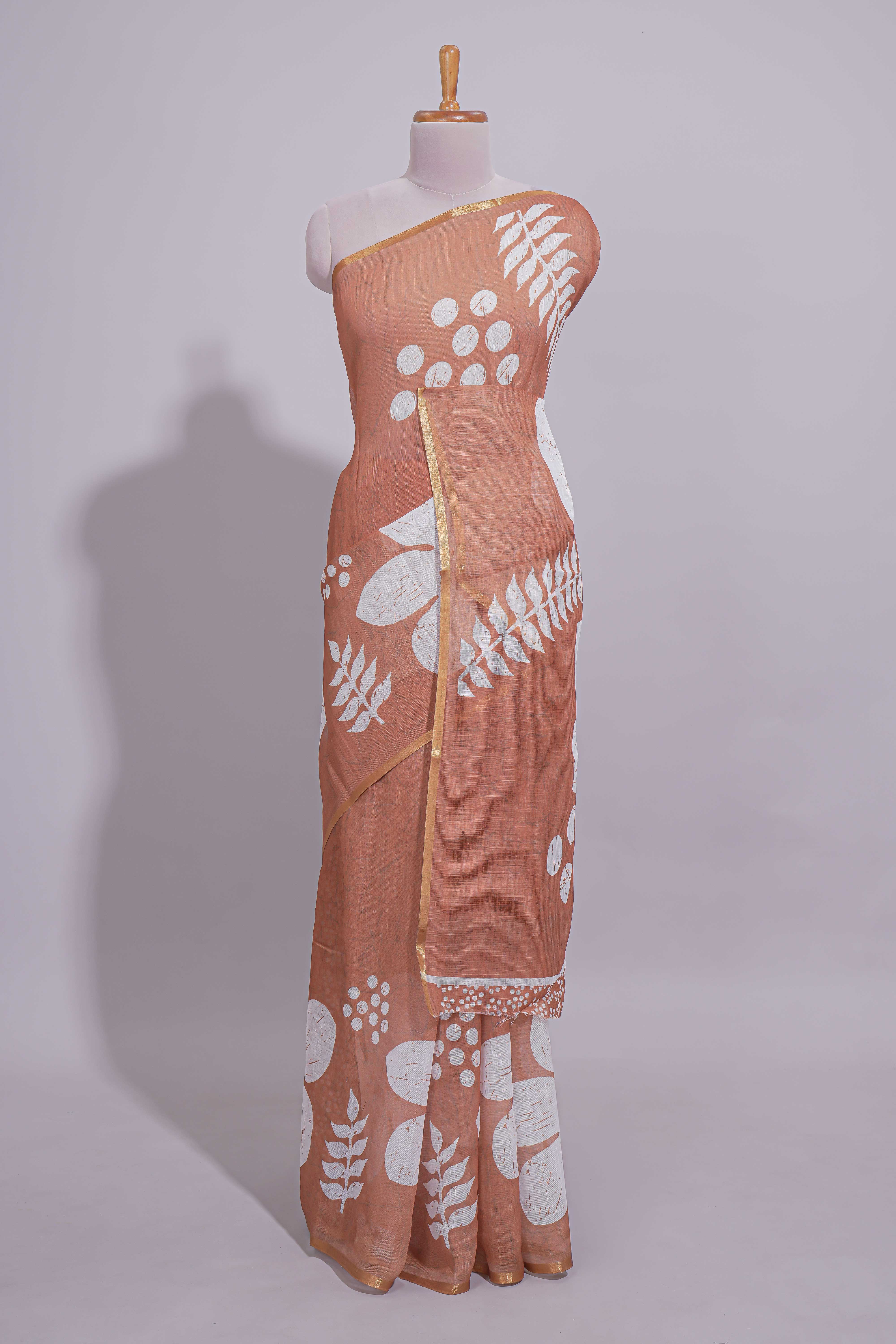Brown linen saree with bold white floral and geometric prints finished with a subtle metallic border along with matching blouse