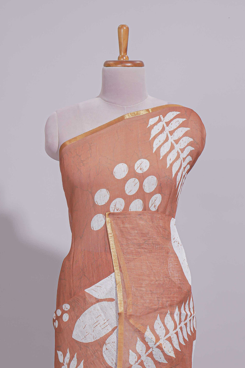 Brown linen saree with bold white floral and geometric prints finished with a subtle metallic border along with matching blouse