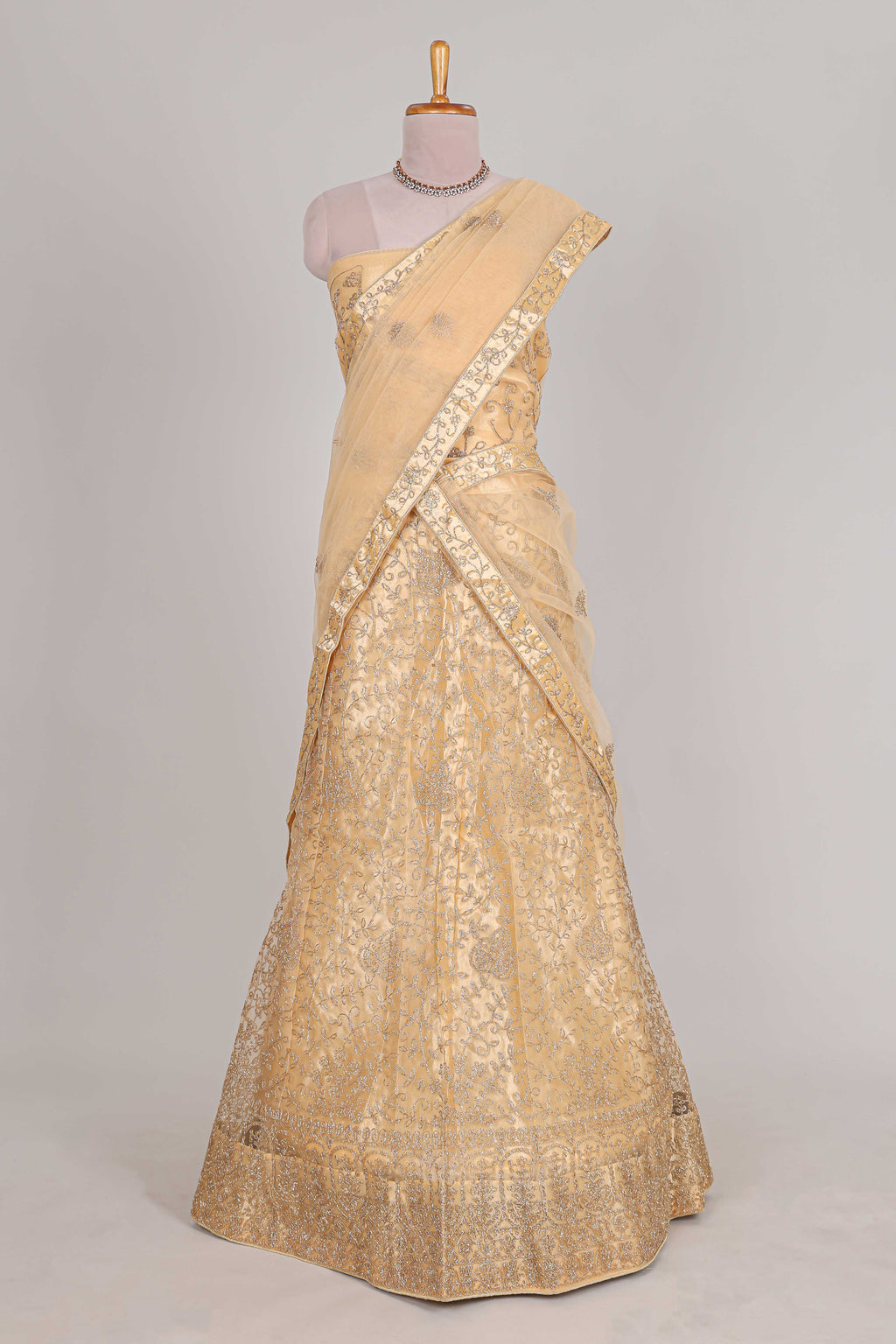 Cream colour net lehenga featuring delicate embroidery with a borderless design paired with a matching self shawl