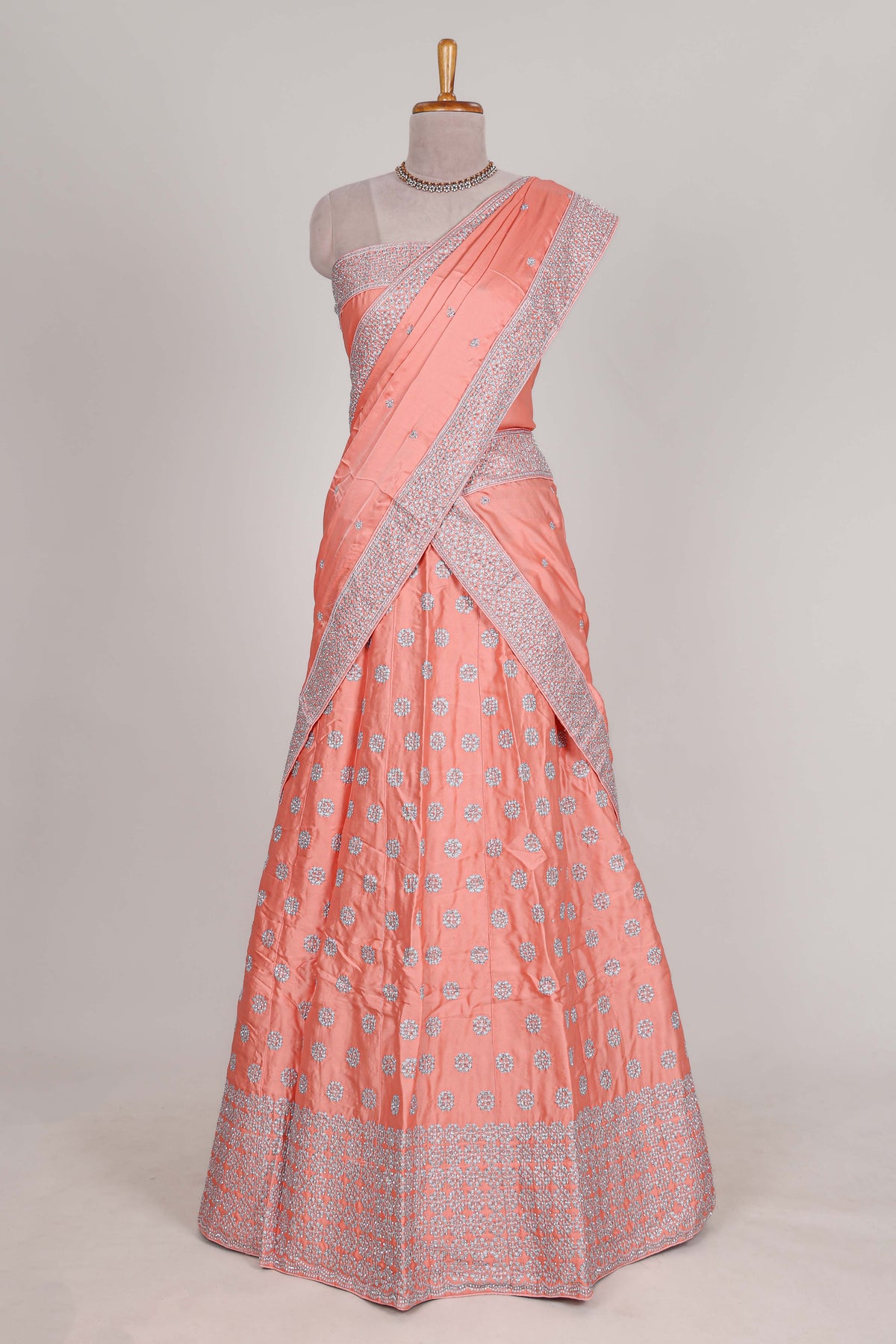 Peach satin lehenga featuring delicate embroidery with a bordered design paired with contrast shawl