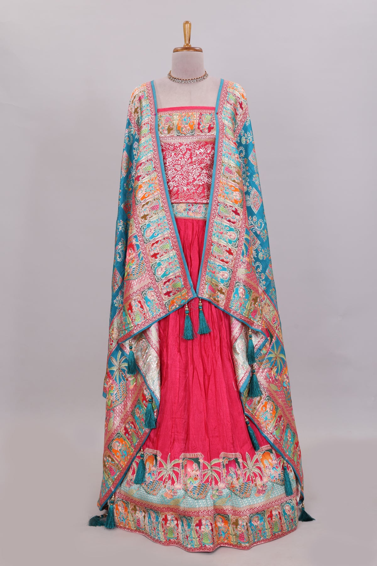 Rani pink plain lehenga featuring with human figure motifs with floral and ornamental detailing border Paired with a teal blue floral designed  shawl