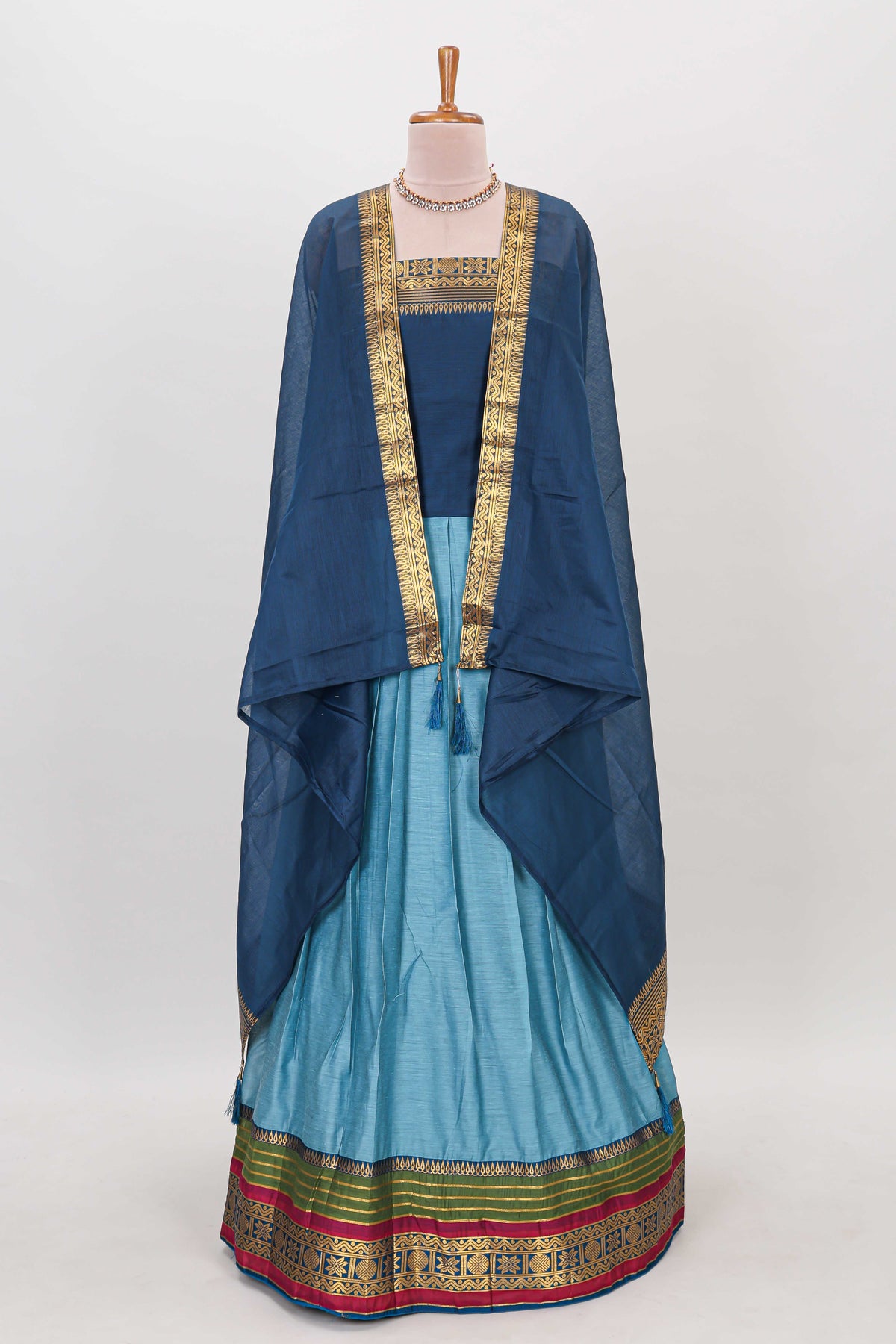 Light blue shade plain lehanga featuring contrasting zari border and blouse paired with dark blue shawl