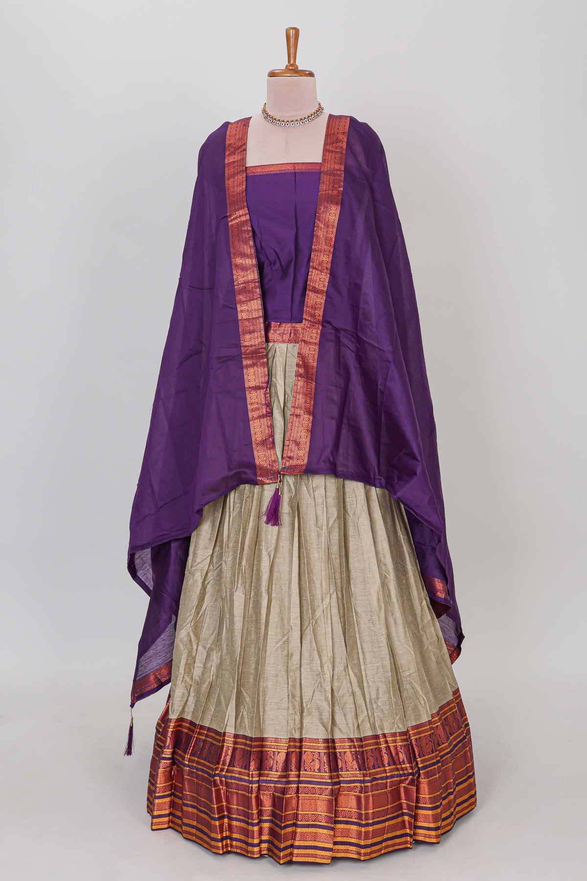 Beige shade plain lehanga featuring contrasting zari border and blouse paired with violet shawl