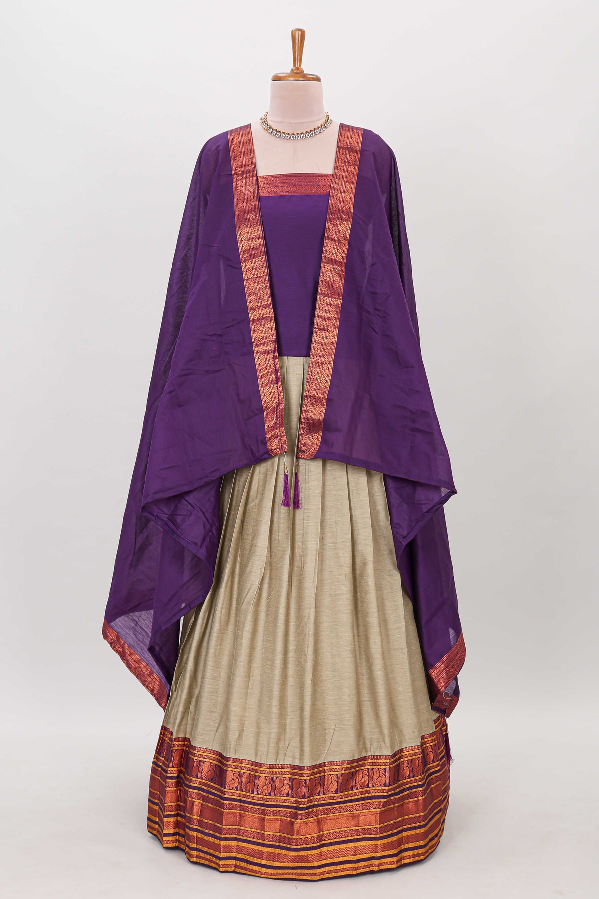 Beige shade plain lehanga featuring contrasting zari border and blouse paired with violet shawl