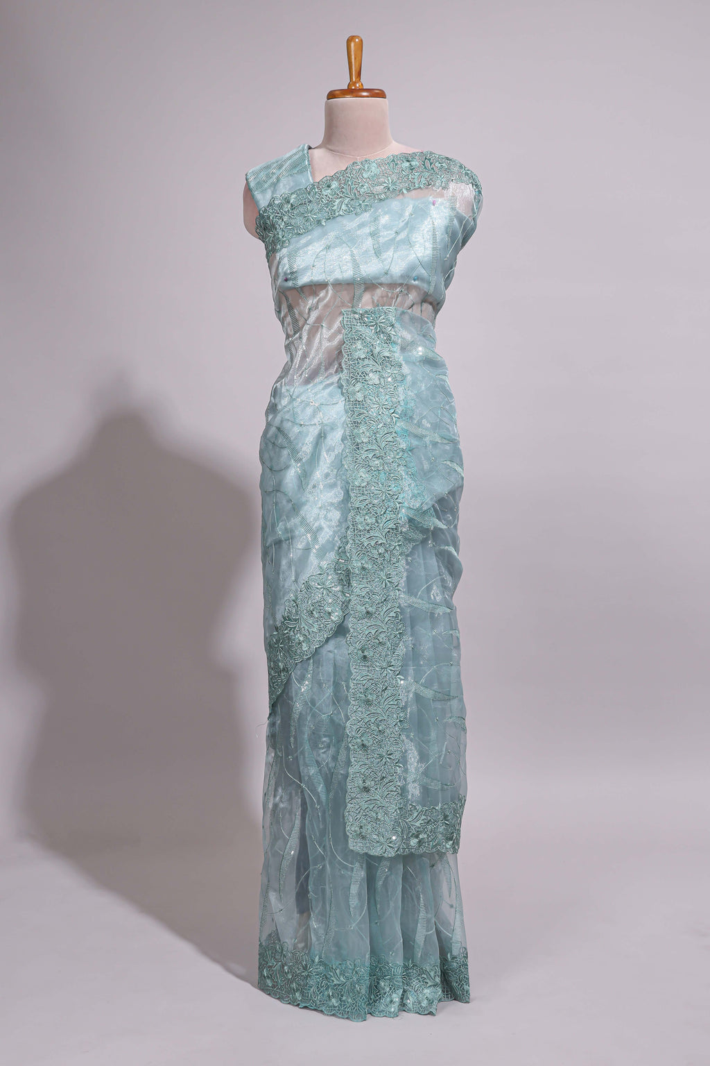 Pastel blue organza saree featuring delicate floral embroidery, intricate lace detailing on the border and pallu with a scalloped finishing along with matching blouse