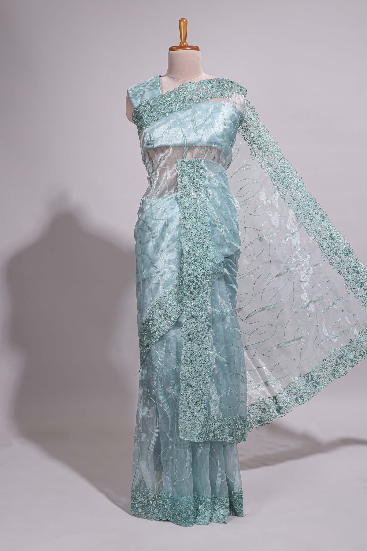 Pastel blue organza saree featuring delicate floral embroidery, intricate lace detailing on the border and pallu with a scalloped finishing along with matching blouse