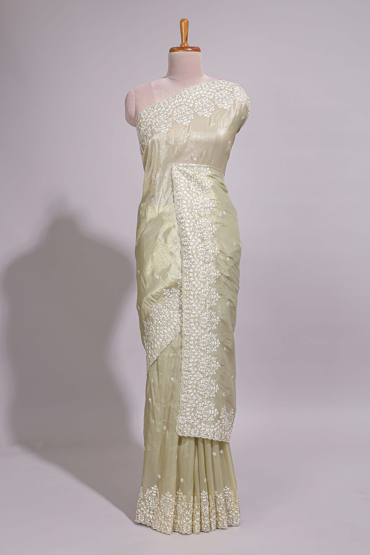 Pastel ivory organza saree with delicate floral embroidery intricate lace border and scalloped pallu detailing