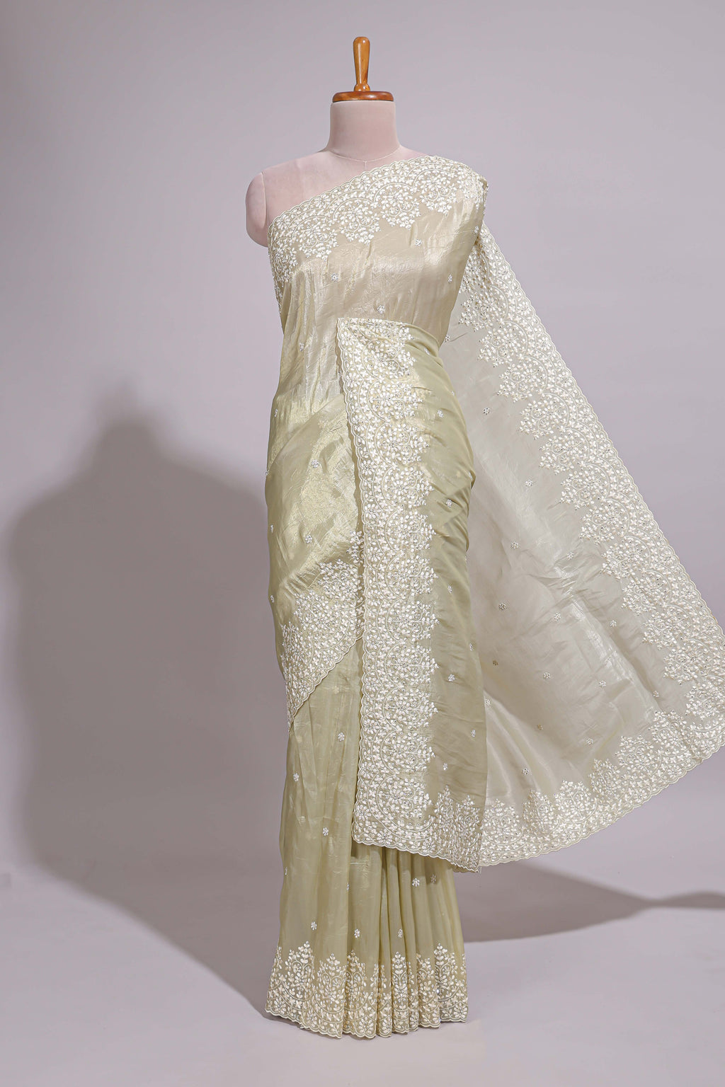 Pastel ivory organza saree with delicate floral embroidery intricate lace border and scalloped pallu detailing