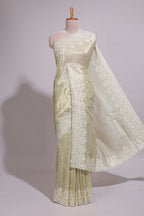 Pastel ivory organza saree with delicate floral embroidery intricate lace border and scalloped pallu detailing