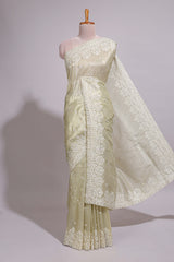 Pastel ivory organza saree with delicate floral embroidery intricate lace border and scalloped pallu detailing