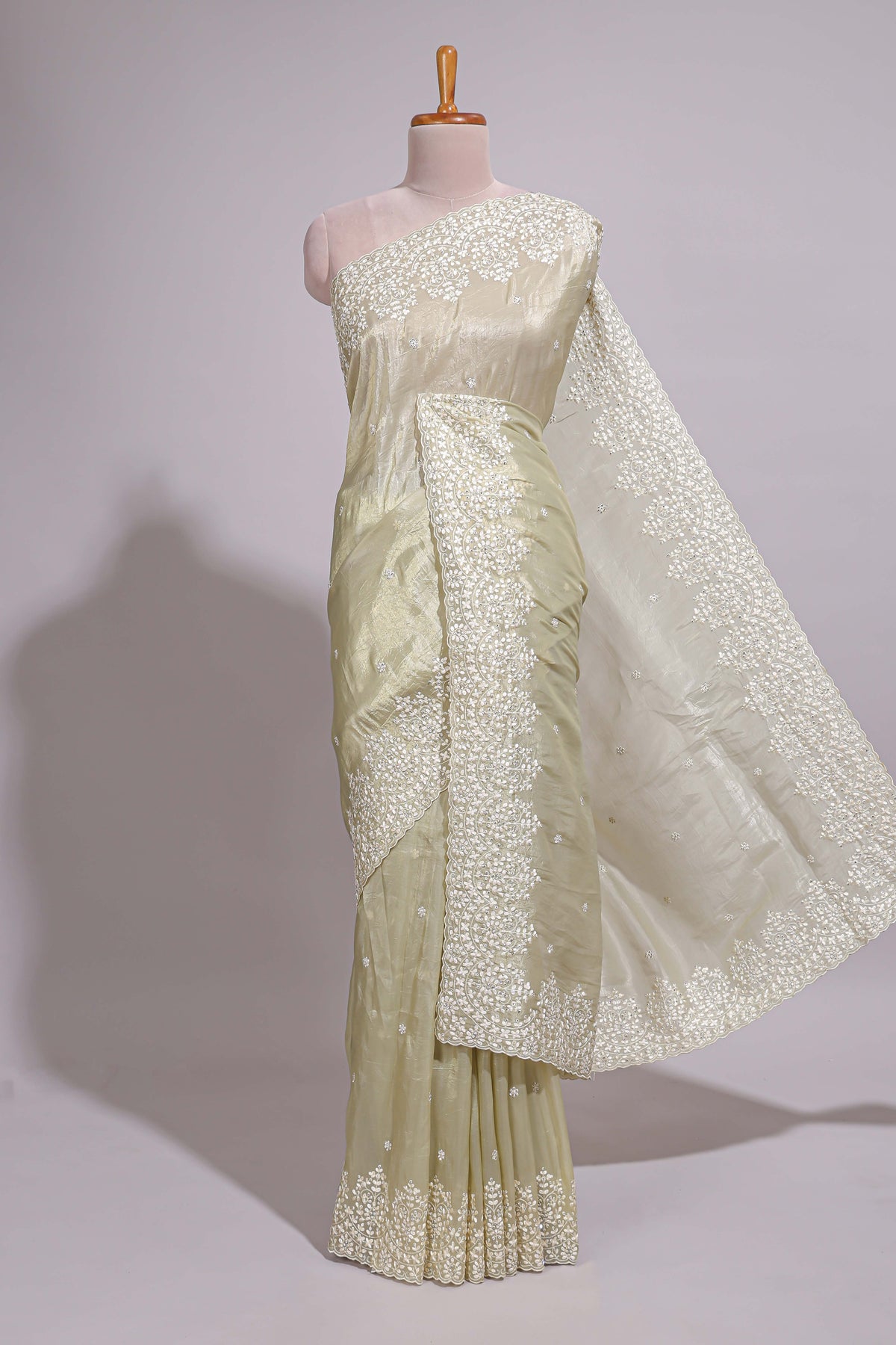 Pastel ivory organza saree with delicate floral embroidery intricate lace border and scalloped pallu detailing