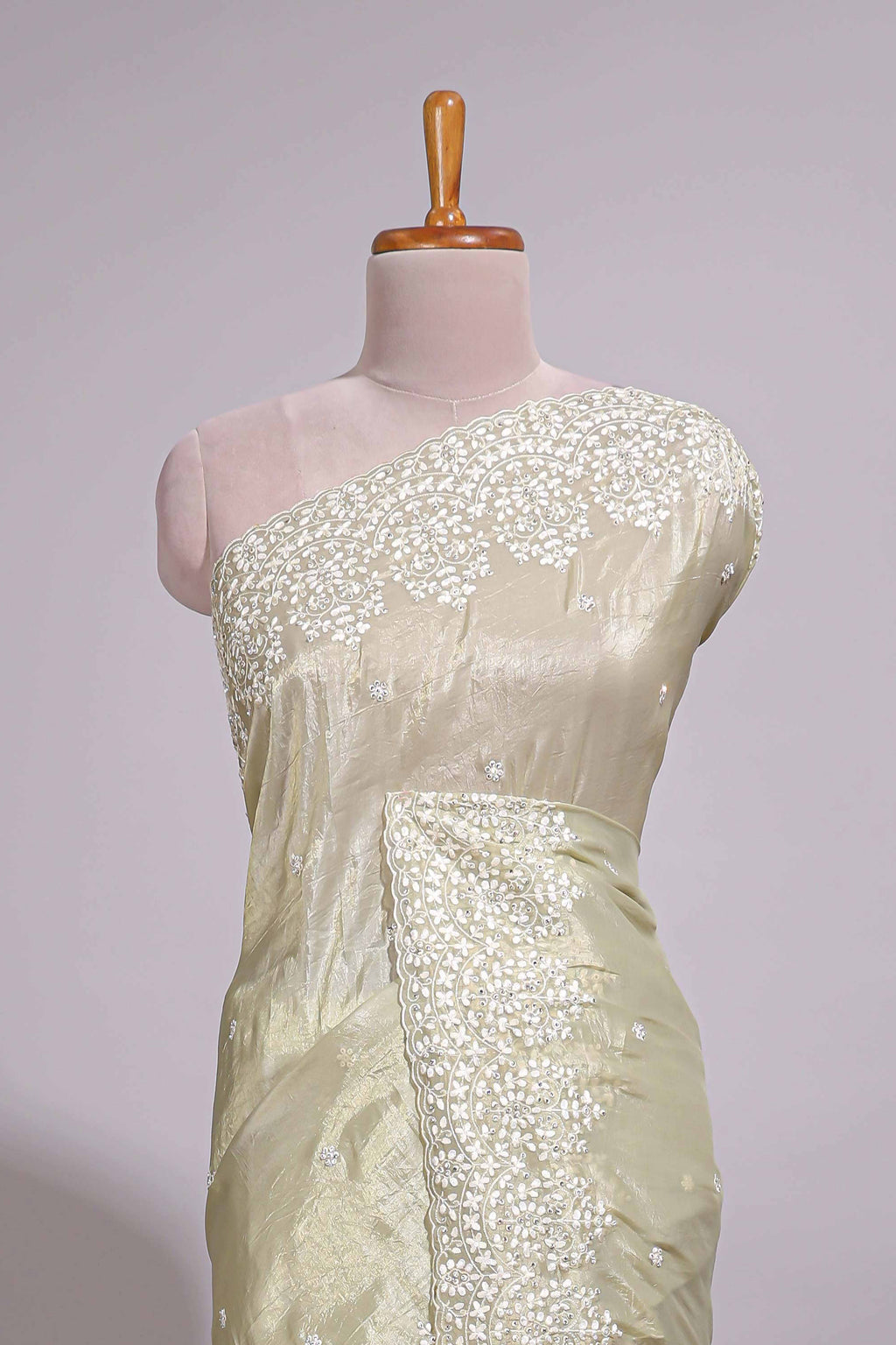 Pastel ivory organza saree with delicate floral embroidery intricate lace border and scalloped pallu detailing