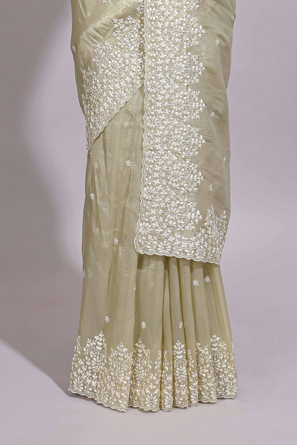 Pastel ivory organza saree with delicate floral embroidery intricate lace border and scalloped pallu detailing
