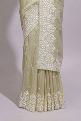 Pastel ivory organza saree with delicate floral embroidery intricate lace border and scalloped pallu detailing