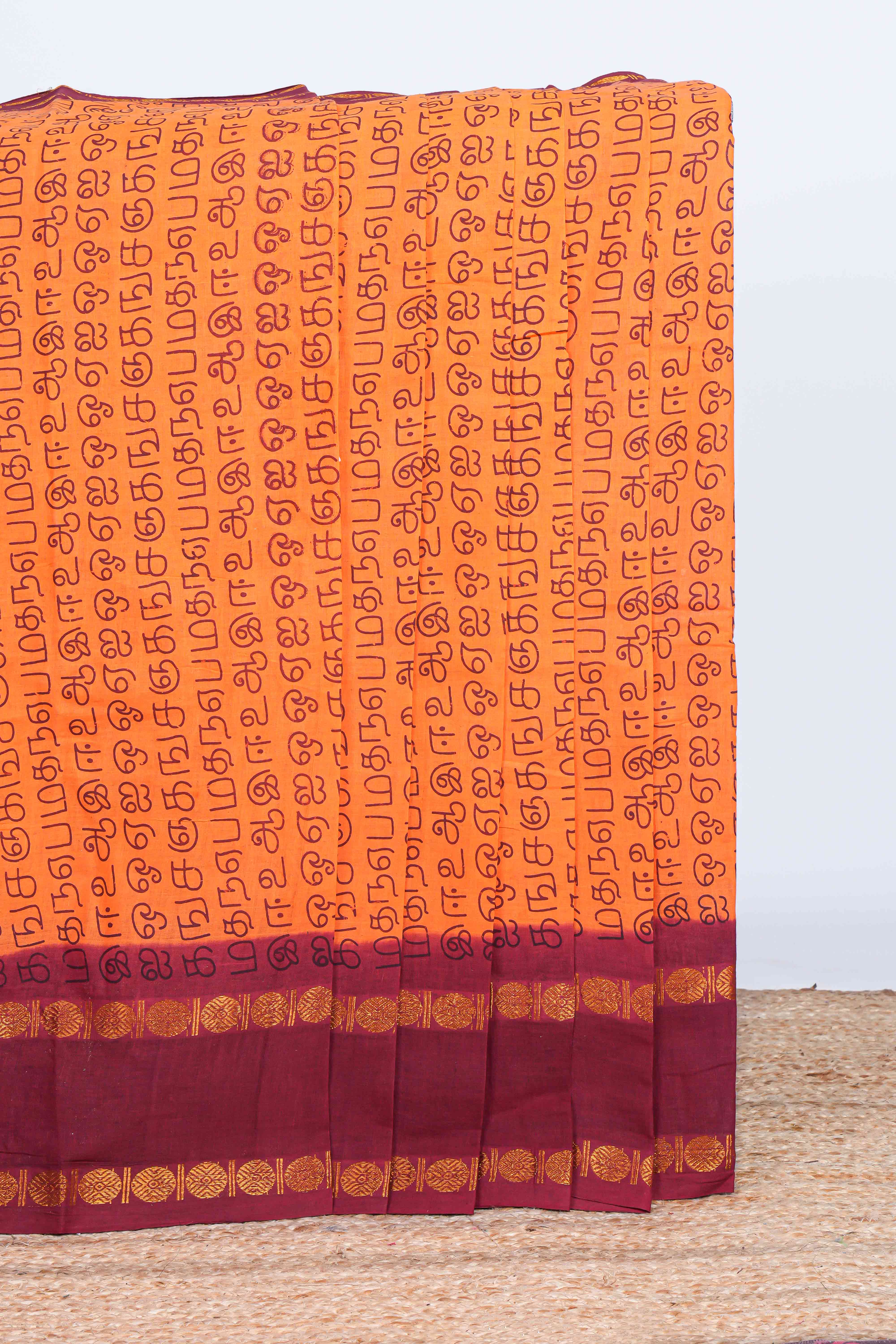 Orange tamil script print sungudi cotton saree with contrast zari bentex border and pallu