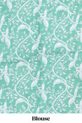 Green Tussar saree with a floral body featuring bird motifs a printed pallu with tassels and a matchingfloral blouse piece