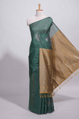 Bottle green tussar saree with subtle silver woven motifs paired with a rich antique gold zari pallu with tassels with contrast blouse piece
