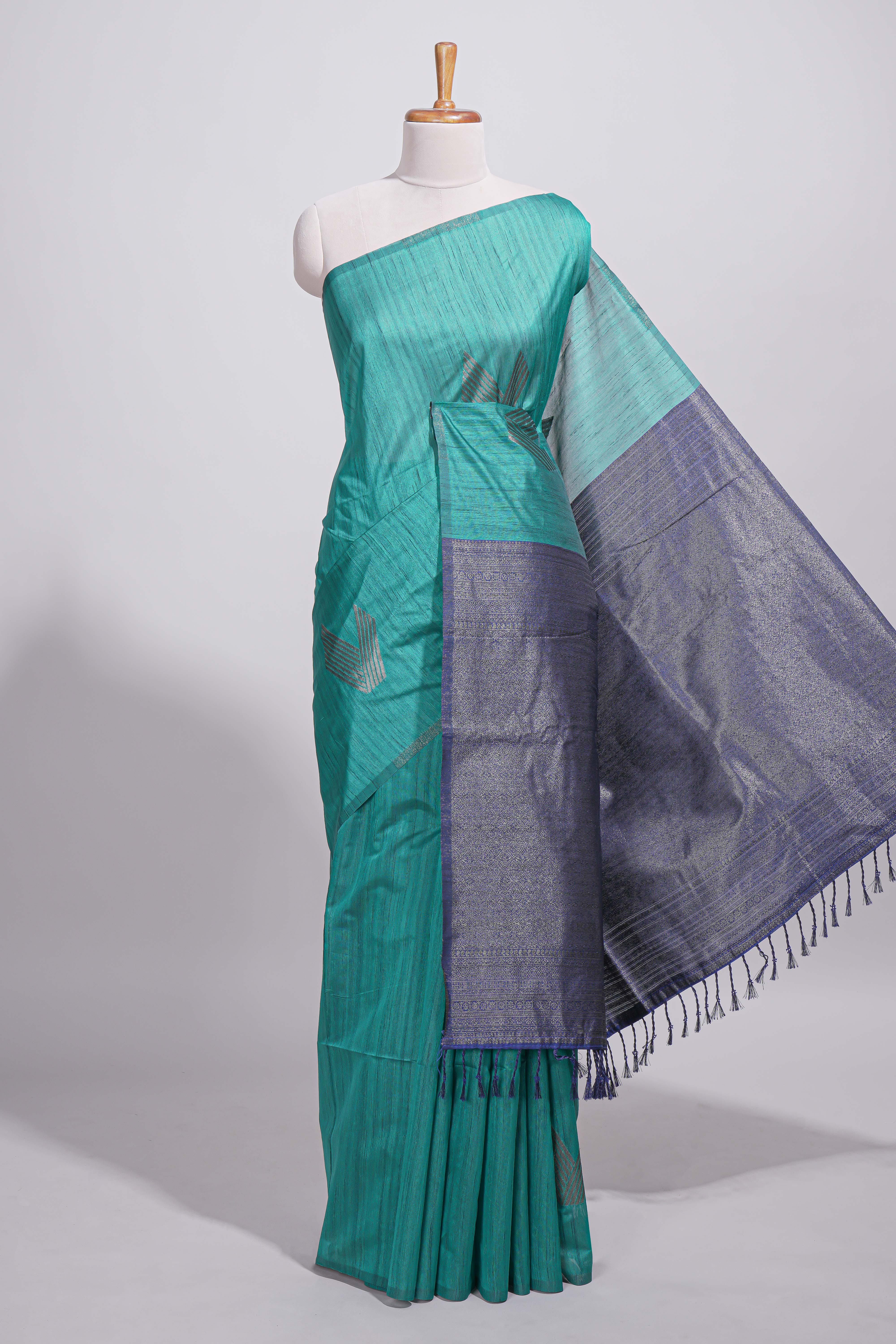 Peacock green tussar saree with subtle silver woven motifs paired with a rich zari pallu with tassels with contrast blouse piece