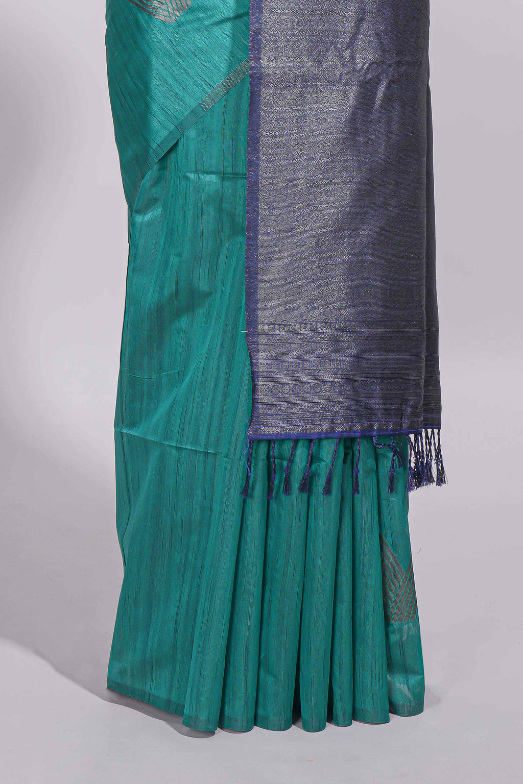 Peacock green tussar saree with subtle silver woven motifs paired with a rich zari pallu with tassels with contrast blouse piece