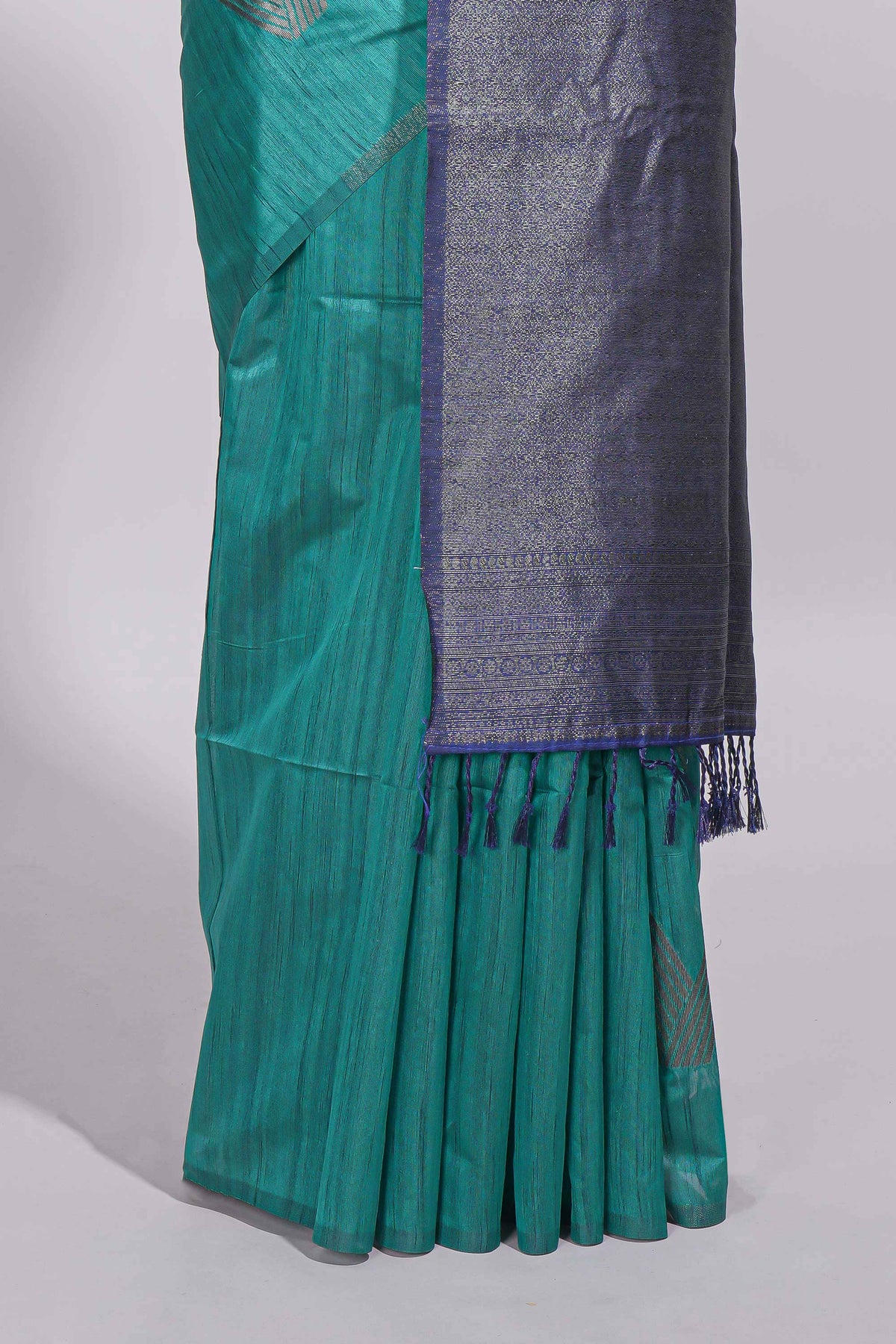 Peacock green tussar saree with subtle silver woven motifs paired with a rich zari pallu with tassels with contrast blouse piece