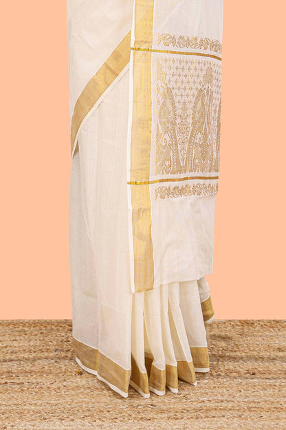 Cream Kerala cotton saree highlighted with delicate zari stripes and a stunning golden peacock zari pallu